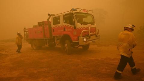 Firefighters protect a property from bushfires burning near the town of Bumbalong south of Canberra