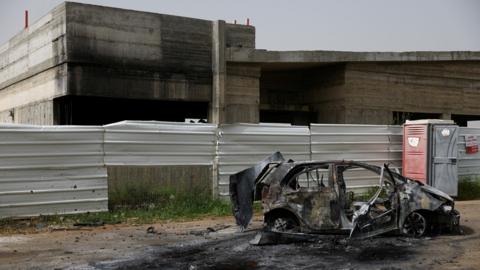 A destroyed vehicle stands outside a damaged community centre in Arab al-Aramshe, northern Israel, the day after a Hezbollah drone and missile attack (18 April 2024)