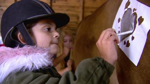 Young girl painting a pony at a party