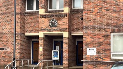 Norwich Crown Court is a red brick building, with stone lintels and steps, with chrome hand rails to the staircase. The Royal Crest is mounted above the main entrance door.
