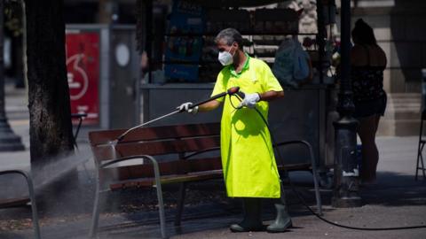 A municipal worker cleans a bench at Catalonia square in Barcelona on July 18, 2020.