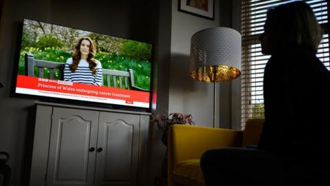 A woman watches Catherine on BBC News on a screen
