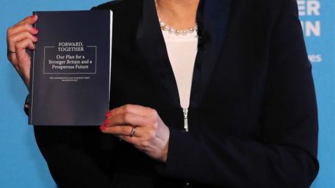 PM Theresa May holding manifesto