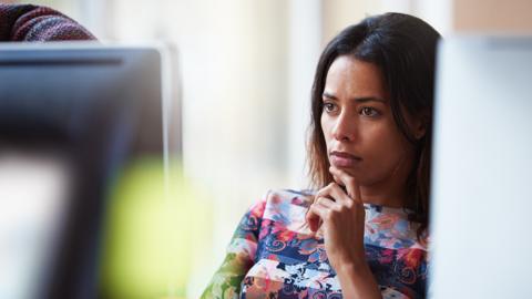 A woman working in an office looking at a computer screen