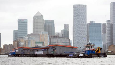 RNLI station being hauled along the Thames under cloudy skies