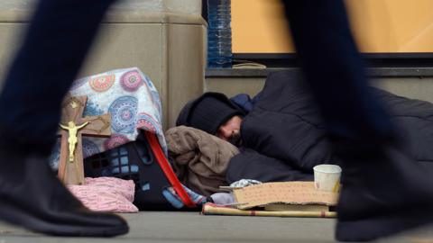 A woman passes a homeless man in Barcelona, January 2019