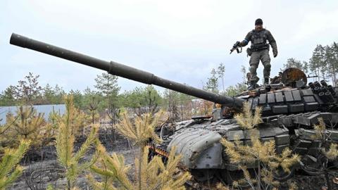 A Ukrainian serviceman stands on the turret of a destroyed Russian army tank not far from the Ukrainian capital of Kyiv on April 3, 2022