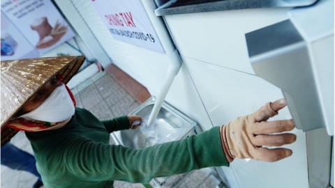 A woman keys in her details to collect rice from a "rice ATM".