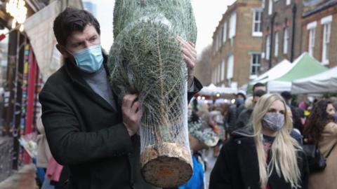 Man buying Christmas tree, wearing a face mask
