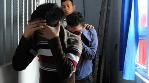 Two Indonesian men walk into a cell prior to their trials at a sharia court in Banda Aceh on May 17, 2017