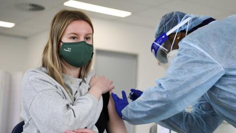 A young woman getting vaccinated by a nurse in full protective wear in Canberra, Australia