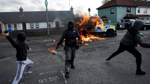 Young hooded men throw a petrol bomb at a police vehicle in Londonderry