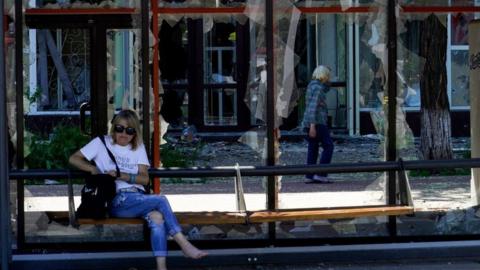 Woman sits at bus stop in Mariupol on 4 June