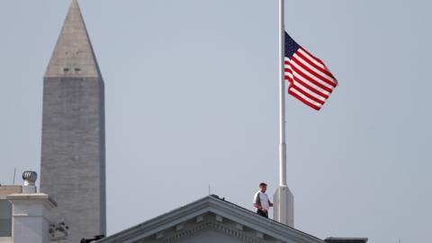 A worker lowers the flag over the White House in Washington to half-staff i