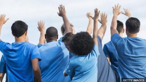 Children in blue shirts jump up and down