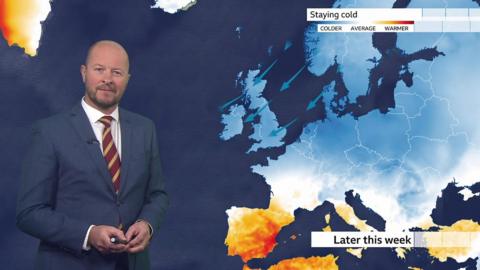 Darren Bett stands next to a chart denoting temperatures across Europe.