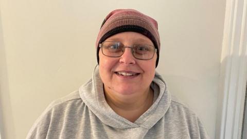 Woman wearing woollen hat and glasses with a grey hoodie