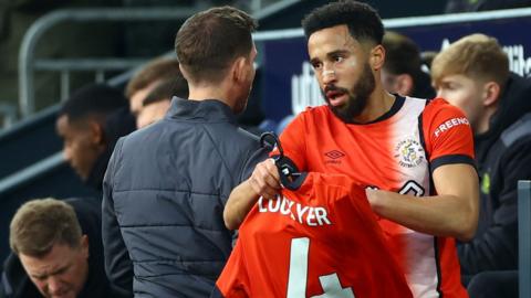 Luton Town's Andros Townsend celebrates scoring their first goal and holds a shirt to support of Luton Town's Tom Lockyer who is recovering following a cardiac arrest