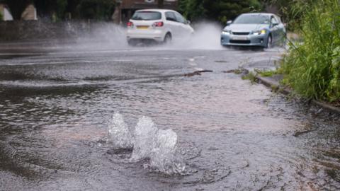 A burst water main floods a street