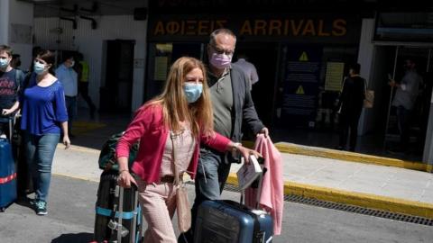 Tourists pull their suitcases as they leave the international airport of Heraklion upon their arrival to spend their holidays on the island of Crete on May 14, 2021