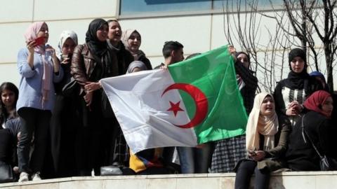 Algerian protesters hold up a national flag