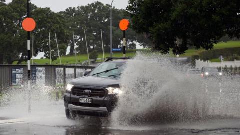 A car drives on a flooded street in Auckland, New Zealand