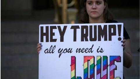 A protester holds a sign in front of the new Trump International Hotel on Pennsylvania Avenue in Washington, DC, USA, 12 September 2016