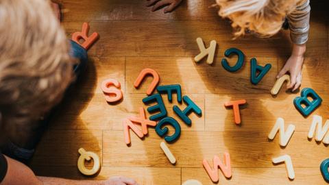 A parent and child playing with plastic letters