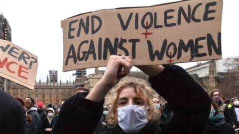 A woman holds a placard saying end violence against women