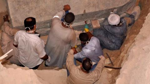 A photo from the Egyptian Ministry of Antiquities shows workers preparing to open the black granite sarcophagus