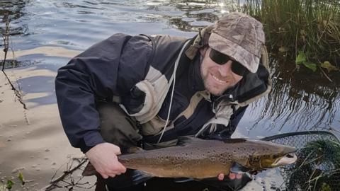 A picture of Scott Sanderson holding a fish