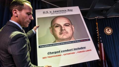 Photo of FBI poster for Lawrence Roy at a 2020 press conference where charges against him were announced.