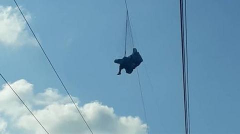 A paraglider is seen suspended from a wire in Táchira state