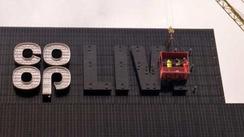 Construction workers outside tha Arena up in front of a unfinished Co-Op Live sign