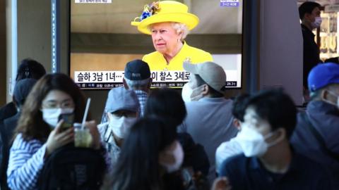 Seoul, where people walk past with the news explaining the death of the Queen