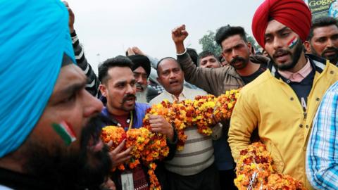 People hold a garland as they shout patriotic slogans before the arrival of Indian Air Force pilot, who was captured by Pakistan on Wednesday, near Wagah border, on the outskirts of the northern city of Amritsar, India, March 1, 2019