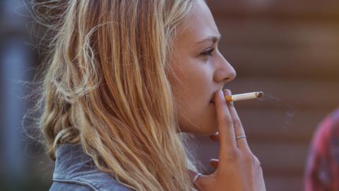 Blonde woman smoking cigarette - stock photo