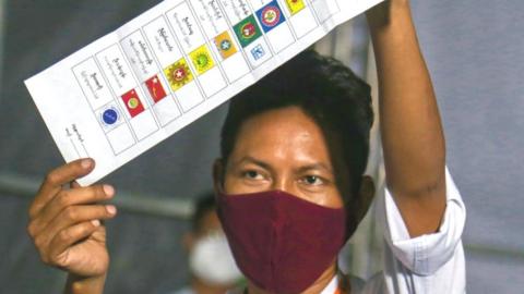 Woman holding a list of election candidates in Myanmar