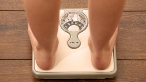 Young girl weighing herself on bathroom scales