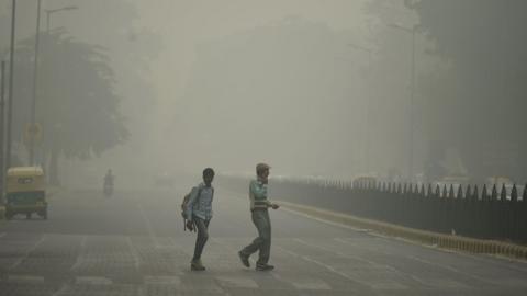 Two pedestrians on road in New Delhi engulfed in smog from last year