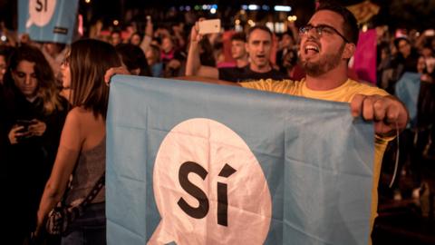 Crowds listen to Catalan President Carles Puigdemont speak via a televised press conference at the Placa de Catalunya on October 1, 2017 in Barcelona