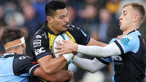 Sio Tomkinson of Dragons is tackled by Teddy Williams and Cameron Winnett of Cardiff