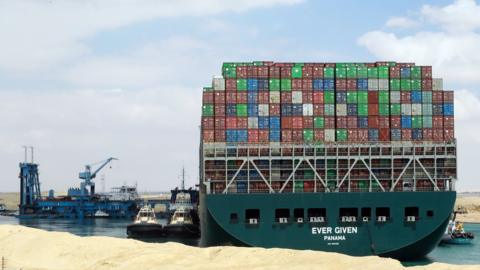 Tug boats and a dredging vessel attempt to refloat the Ever Given in Egypt's Suez Canal (26 March 2021)