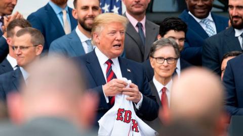US President Donald Trump (C) holds a Boston Redsox's jersey that was given to him as he welcomed the 2018 World Series Champions to the White House in Washington, DC, on May 9, 2019