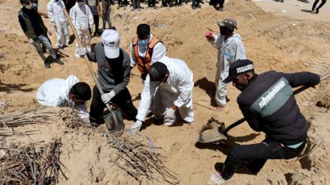 Palestinian civil defence workers dig mounds of earth in the grounds of Nasser hospital in Khan Younis, in the southern Gaza Strip (21 April 2024)
