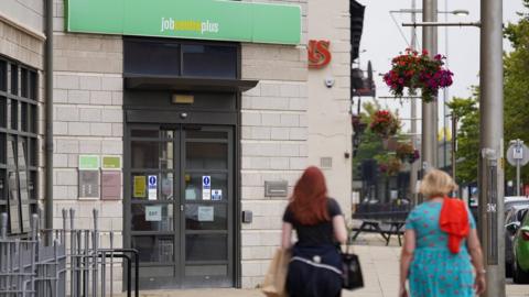 Two women walk past a job centre