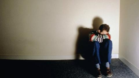 Man sitting the corner of a room