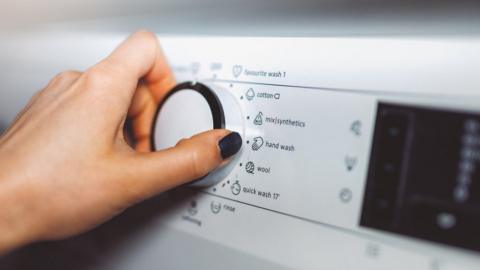 hand on washing machine controls