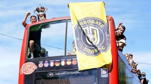 Harrogate Town's Josh Falkingham holds the trophy as he celebrates with team-mates during an open top bus tour around Harrogate