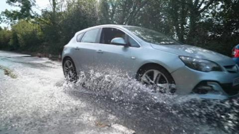 Car drives through water leak